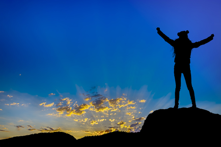silhouette achievements successful arm up girl is on top of hill celebrating success with sunsetの写真素材
