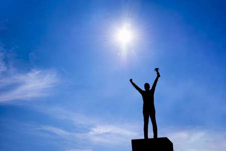 silhouette,a man holding up a gold trophy cupの写真素材