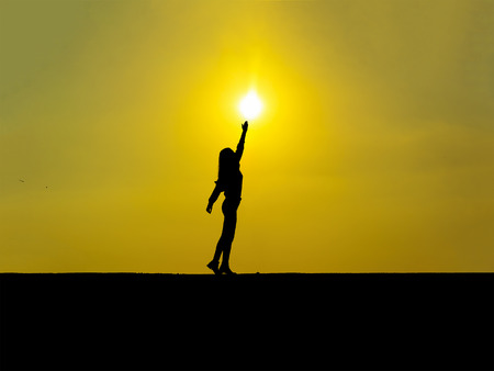 silhouette-young girl touching the sun at sunsetの写真素材