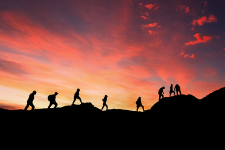 eight friends walk on mountain path in sunsetの写真素材