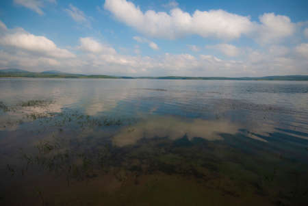Landscape of a lake with blue sky and clouds reflected in water
