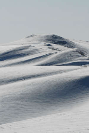 snow floor, snow texture, snowy peaks in cold sunny weather, cloudy snow landscape. Windblown snow...