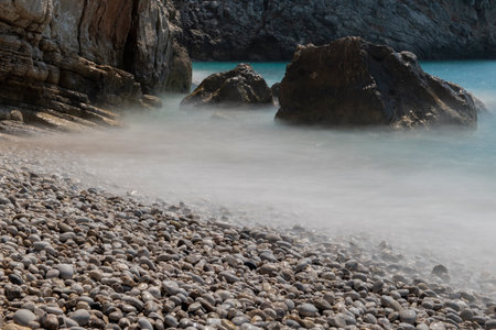 Long exposure by the sea. Waves break against stones. Sunset at the beach. Long exposure at night by the sea. Patara Beach Antalya Turkeyの写真素材