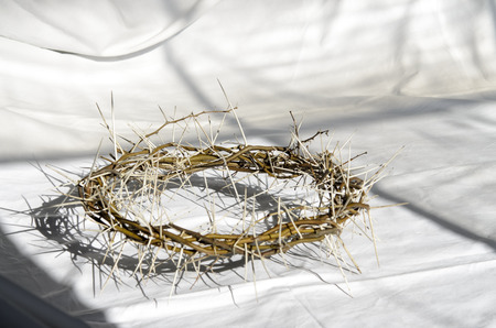 crown of thorns reminds the passion of the christ. resting on a white linen cloth with an olive branchの写真素材