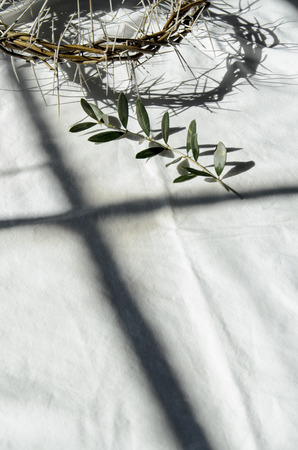 crown of thorns reminds the passion of the christ. resting on a white linen cloth with an olive branchの写真素材