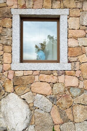 Open window on a block of granite wall with a vase of ears of corn.の写真素材