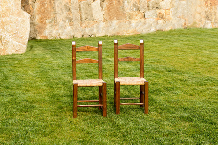 A pair of lonely wooden chairs on the green grassの写真素材