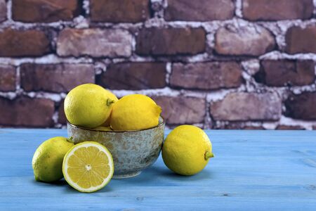 Ripe yellow lemons arranged in a gray bowl. In the background of raw red brick wall.の写真素材