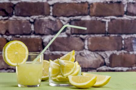 Lemon juice with glass and straw and freshly cut lemonsの写真素材