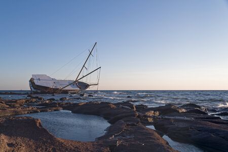 Sailboat, stranded along the coast on the cliff of Sardinia in the Mediterranean Sea.の写真素材