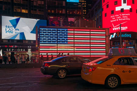 New York, USA - june 06, 2015: Time Square at night. Signage lights illuminate the road. A flag of the USA shines with its colors. Taxis, cars and people passing. Time Square, New York.のeditorial素材
