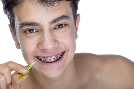 Cute teenager with white background, wearing braces on his teeth. Use a small toothbrush.の写真素材