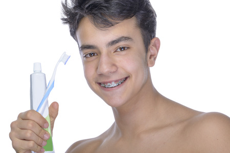 Cute teenager with white background, wearing braces on his teeth. Use toothbrush and toothbrush for cleaning.の写真素材