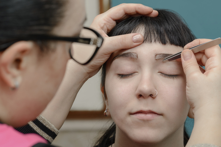 Permanent makeup.Verification of proportions and work preparation. Cosmetologist applying permanent make up on eyebrows- eyebrow tattooの写真素材