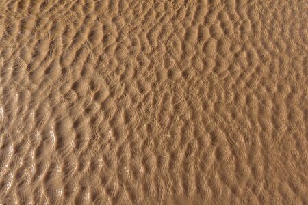 Photograph of small real water waves and reflections for texture. Brown color.の写真素材