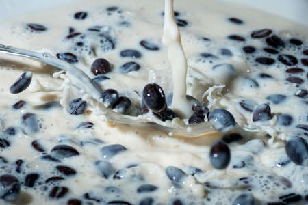 Coffee beans falling on the milk splash. Cup of milk. Concept photography.の写真素材