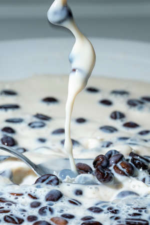Coffee beans falling on the milk splash. Cup of milk. Concept photography.の写真素材