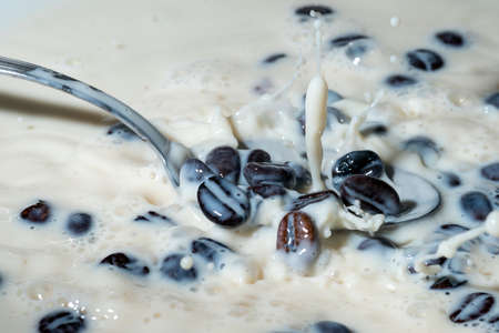 Coffee beans falling on the milk splash. Cup of milk. Concept photography.の写真素材