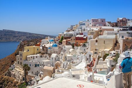 Thira, Greece - 05/20/2015: Gourgeous view from the white walled town of Santorini, Greece, with the ocean, cliffs and caldera of Santorini in the background.のeditorial素材