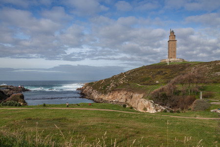 Hercules Tower Lighthouse in Coruna Spain on a sunny day with blue sky and clouds on top of the hillの写真素材