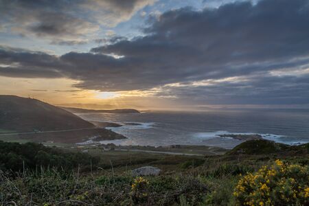a sunset with orange and yellow colours over the sea and coast in coruna, spainの写真素材