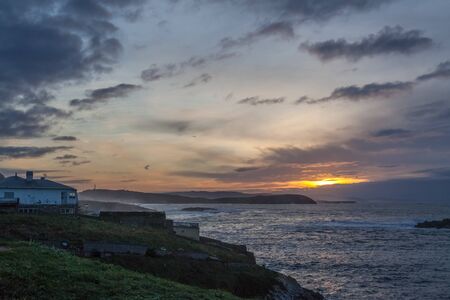 a sunset with orange and yellow colours over the sea and coast in coruna, spainの写真素材