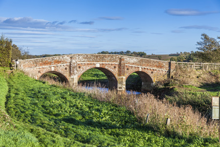Old bridge over river Rother near Bodiam castle on a sunny day with green grass and blue skyのeditorial素材