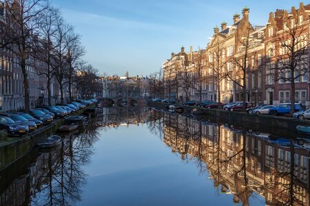 water canals in Amsterdam on a sunny day with traditional architecture reflecting in the waterのeditorial素材