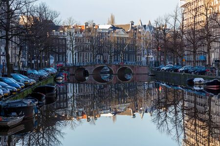 water canals in Amsterdam with a bridge in the middle and traditional architecture
