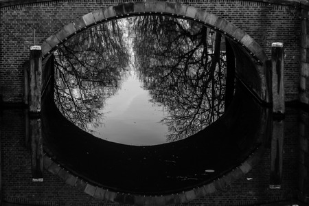 water canals in Amsterdam with a bridge in black and whiteの写真素材