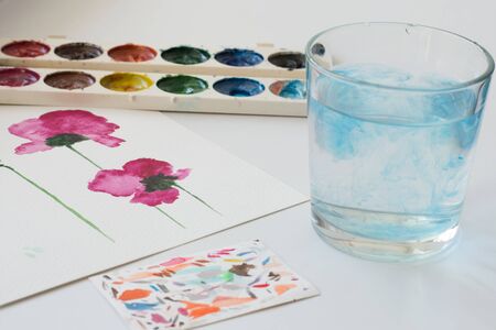 Watercolor painting of pink magnolia flower and artistic tools on white table. Still life composition of artistic workplaceの写真素材