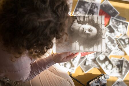 Young woman is sitting on the floor and looking at old photographsの写真素材