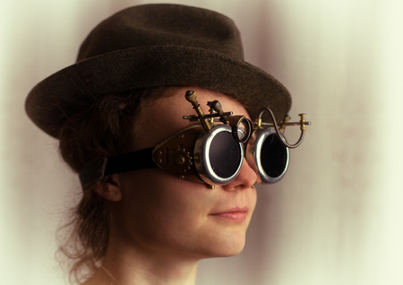 Portrait of attractive steampunk girl wearing googles and hat on light backgroundの写真素材