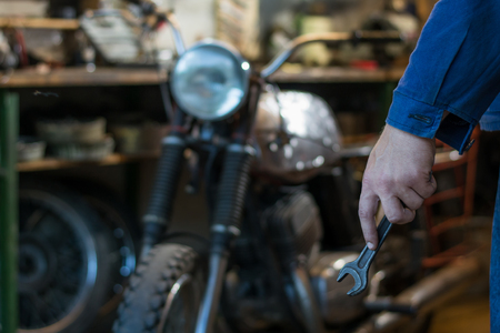 Man's hand holding a car key in garage, on the background of motorcycleの写真素材