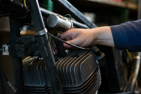 Man's hand repairing motorcycle in the workshopの写真素材