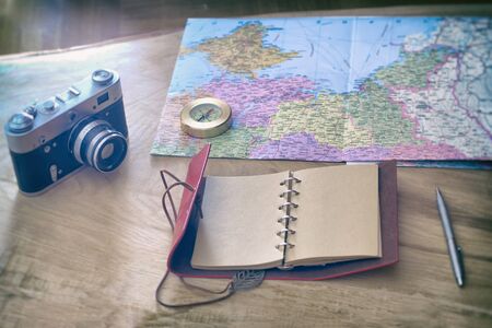Traveler's things: camera, map, notebook, compass on a wooden backgroundの写真素材