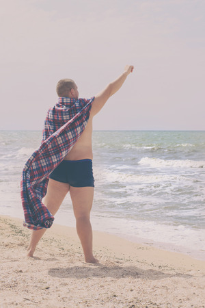 Fat superhero stands on the shore of the seaの写真素材