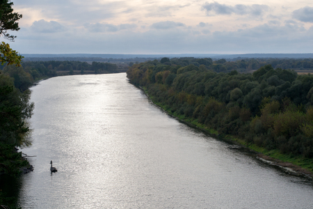 Silhouette of a fisherman near the boat at the riverbankの写真素材