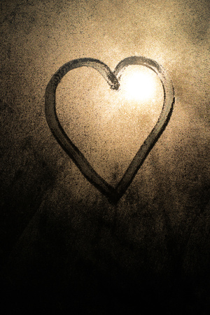 Photo of a heart drawn on a frozen window in the winterの写真素材