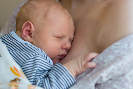 Cute newborn baby sleeping on his mother's breast
