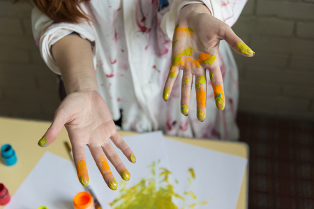 A girl paints a picture with colors using her own handsの写真素材