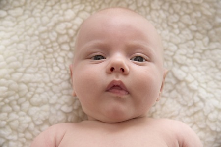 Portrait of a cute newborn child against a white sheepskin