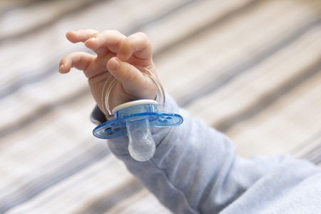 Photo of child's hand holding a pacifier, close-upの写真素材