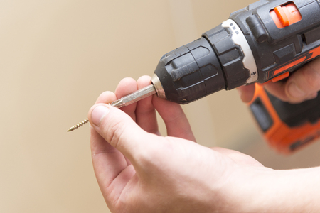 Wireless screwdriver in the hands of a man, the theme of repair work and buildingの写真素材
