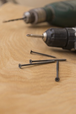 Wireless screwdriver self-tapping screws on a wooden background, the theme of repair work and building, close-upの写真素材