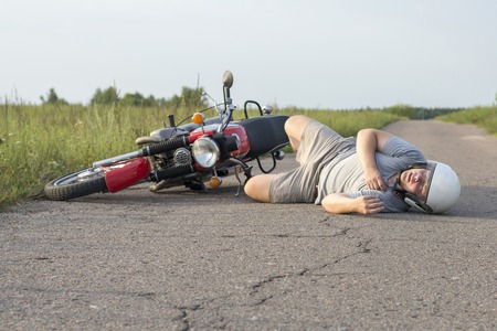 The man is lying on the asphalt near his motorcycle, the theme of road accidentsの写真素材