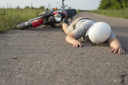The man is lying on the asphalt near his motorcycle, the theme of road accidentsの写真素材