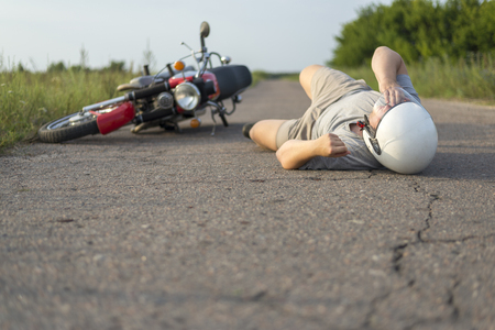 The man is lying on the asphalt near his motorcycle, the theme of road accidentsの写真素材
