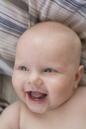 Portrait of a cute naked smiling little baby with two first teeth