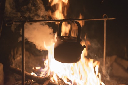The kettle is heated on a bright fire at night outdoorの写真素材